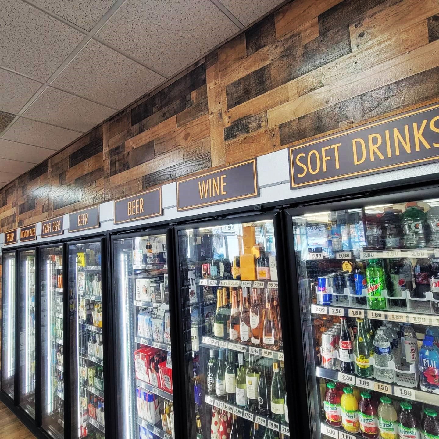 Custom Magnetic PVC signage above coolers in Kakos fine whine and spirits of Birmingham, MI by InkBird Print Studio. Black and gold, simple font block letters.