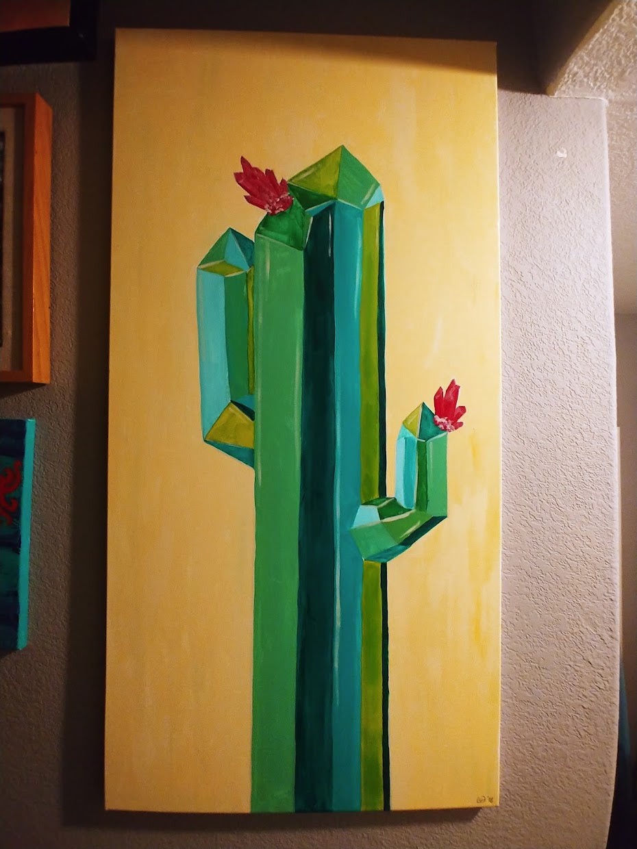 The "Crystal Cactus I" acrylic painting by Claire Davis, offered by InkBird Print Studio LLC, features a tall, stylized geometric cactus in shades of green and blue with red flowers adorning the top and arms, set against a pale yellow background.