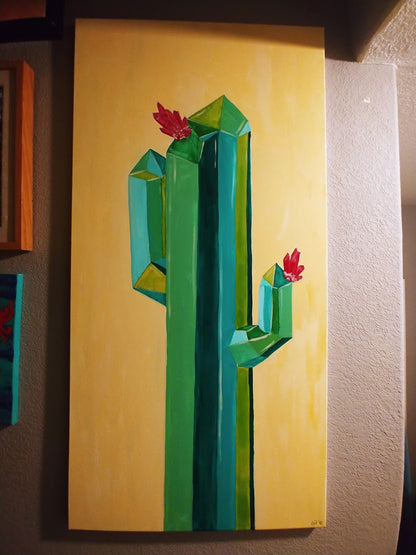 The "Crystal Cactus I" acrylic painting by Claire Davis, offered by InkBird Print Studio LLC, features a tall, stylized geometric cactus in shades of green and blue with red flowers adorning the top and arms, set against a pale yellow background.