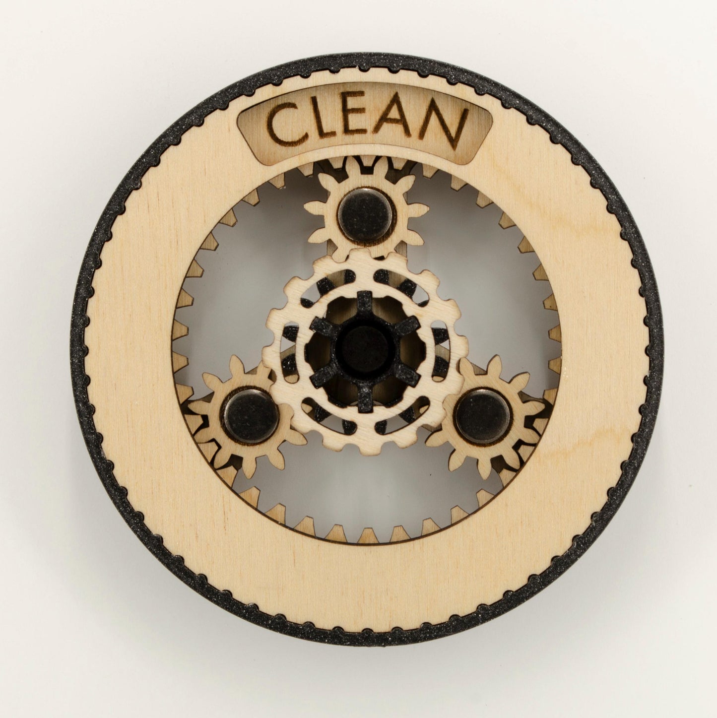 A round dishwasher magnet with rotating planetary gears made of laser-cut wood, enclosed in a 3D-printed PLA housing. The gears can be rotated to reveal either 'CLEAN' or 'DIRTY' in an engraved display window at the top, indicating the dishwasher's status.