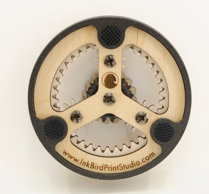 The back of the dishwasher magnet, featuring a wooden frame with a 3D-printed PLA outer ring. Three rubberized feet are embedded in the frame to prevent scratches and provide grip on metal surfaces. The central wooden piece is secured with small screws and has a laser-engraved swirl logo. The website 'www.InkBirdPrintStudio.com' is engraved along the bottom edge, adding a branded touch.