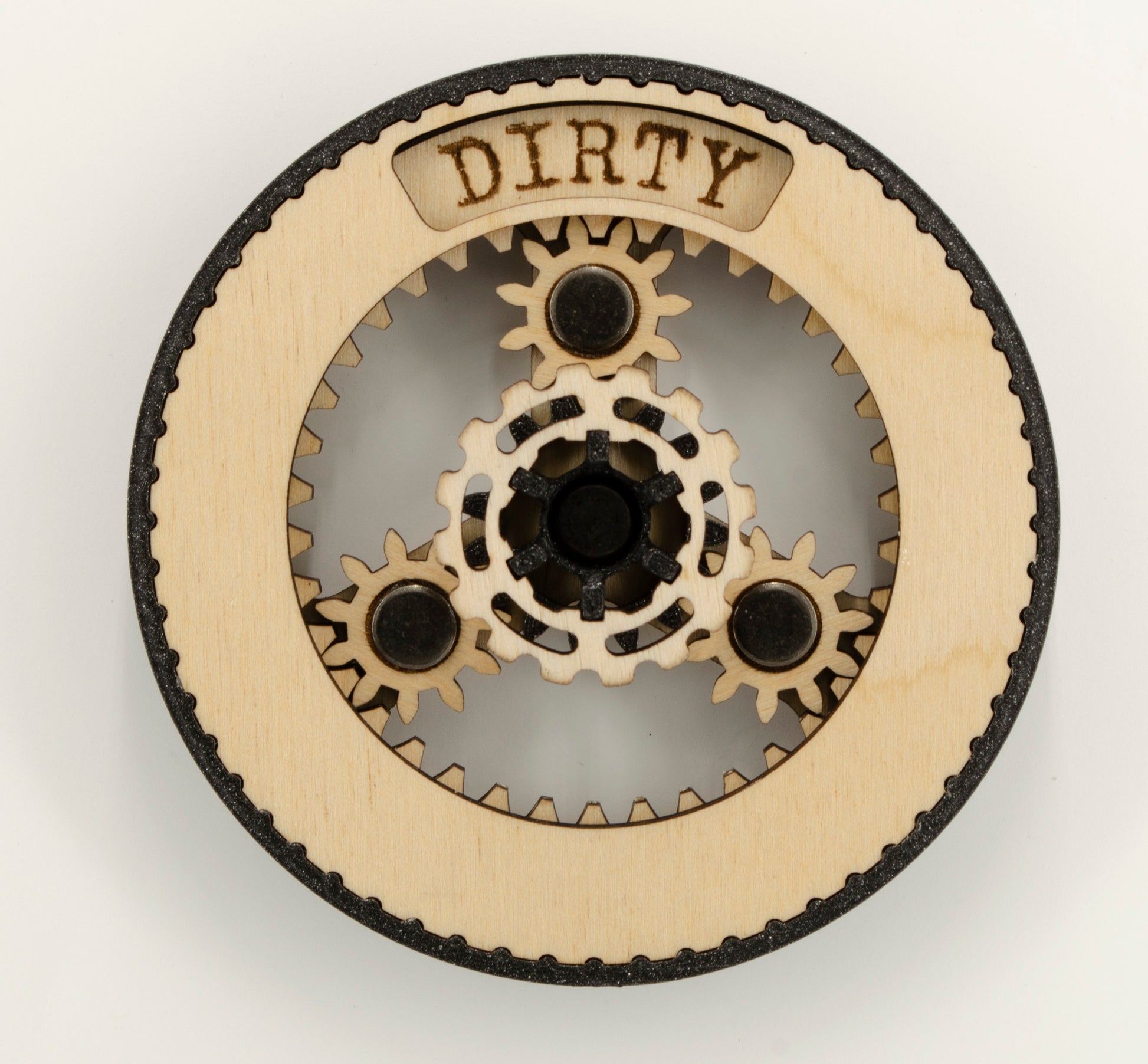 A round dishwasher magnet with rotating planetary gears made of laser-cut wood, enclosed in a 3D-printed PLA housing. The gears move to reveal either 'CLEAN' or 'DIRTY' in an engraved display window at the top, indicating the dishwasher's status.