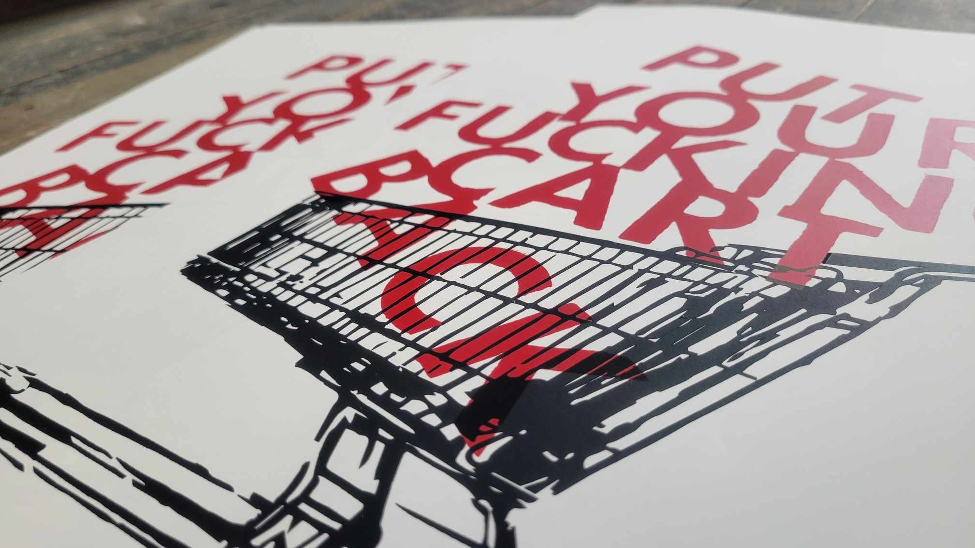 A closeup shot of Claire Davis' 2 color screenprinted piece "Put your cart back"

A 2 color screen print of a shoping cart (black) stacked high with red text spelling out "PUT YOUR F*CKING CART BACK" stacked on top of one another like packages from a store. 2 color handpulled print by Claire Davis. A commentary on anti-social behavior.