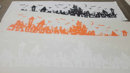 Black, Orange, and White versions of Our Spooky Town Halloween static cling window decoration, renter-friendly, screen-printed on clear cling material and contour cut, featuring haunted houses, eerie trees, bats, ghosts, and a moon, perfect for windows and glass surfaces. 