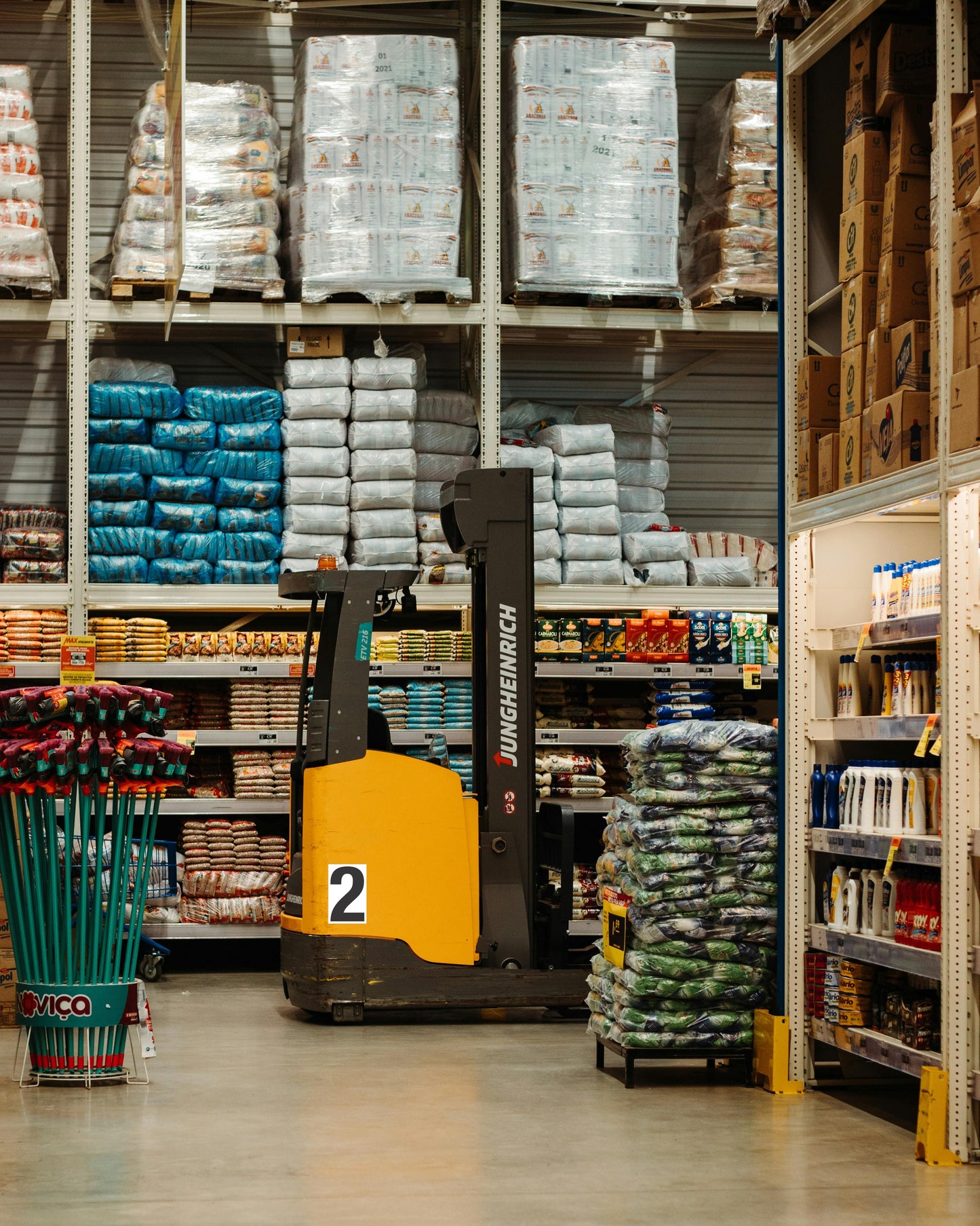 Yellow industrial forklift, vinyl decal, adhesive backing; parked in warehouse aisle with custom pet food and garden supply boxes.