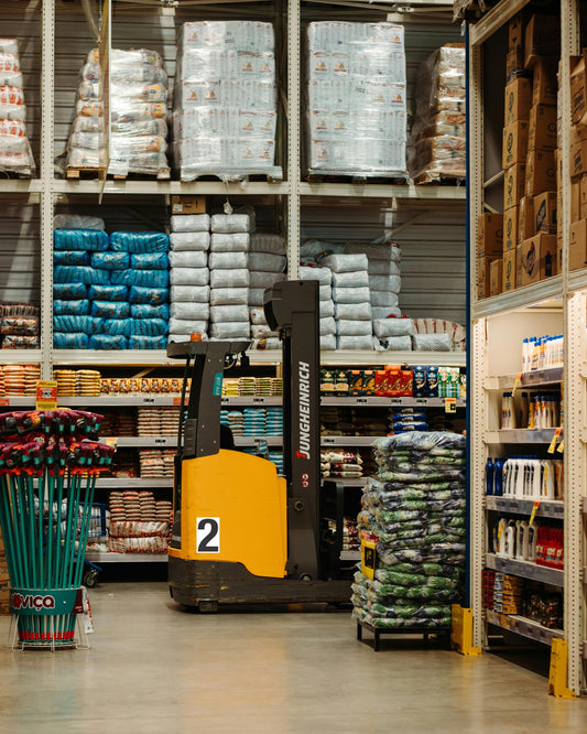 Yellow industrial forklift, vinyl decal, adhesive backing; parked in warehouse aisle with custom pet food and garden supply boxes.