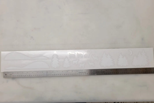 Image of the Winter Scene Static Cling Set by InkBird Print Studio LLC as it will ship to you (on a liner that can be rolled up and reused). These are a renter-friendly way to decorate your window, featuring snowy hills, deer, pine trees, and a moon, all printed in white ink on clear static cling. A ruler at the bottom showcases the scale of these clings.