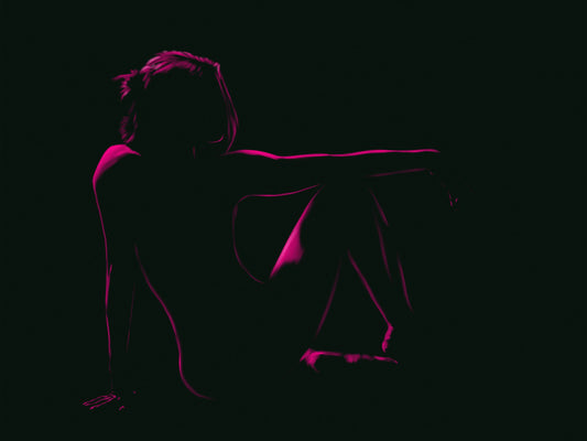 A silhouette of a seated person against a dark background, their outline and posture highlighted by pink lighting. The figure's pose, with one leg bent and an arm resting on it, brings to mind the digital painting techniques seen in "Garnet" by Chris Luberger from InkBird Print Studio LLC.