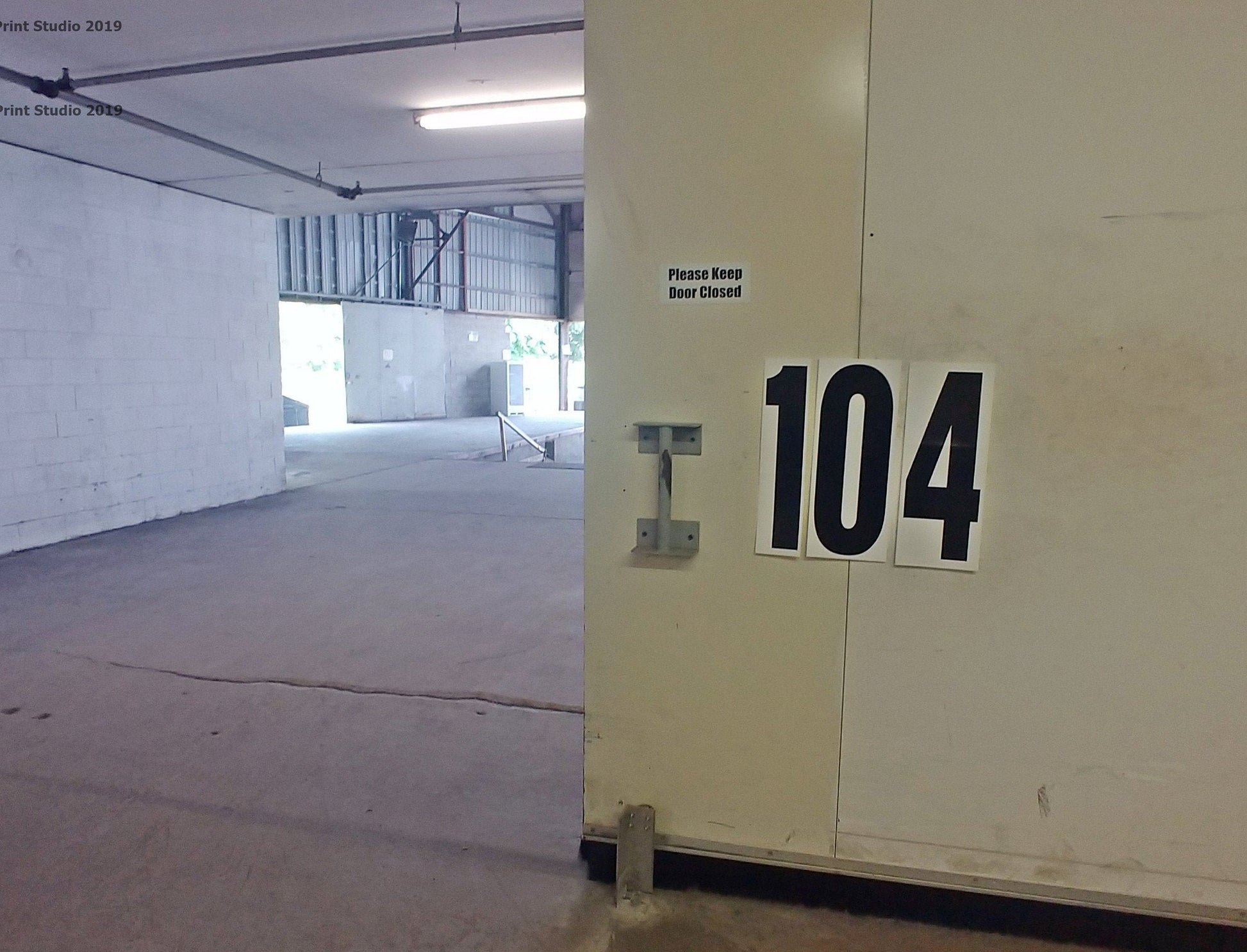 18 inch decals applied to a loading dock door to indicate which door you are are. Showing the numbers 1 0 4 on separate decals. Black ink on white matte vinyl.