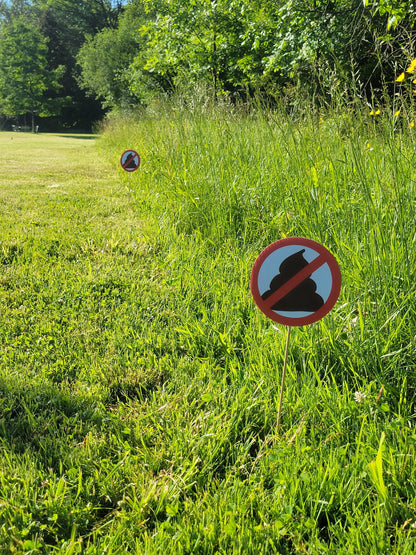 a photo of multiple no pooping yard signs (round, 6 inch diameter) in a row, marking the perimeter of a property. 