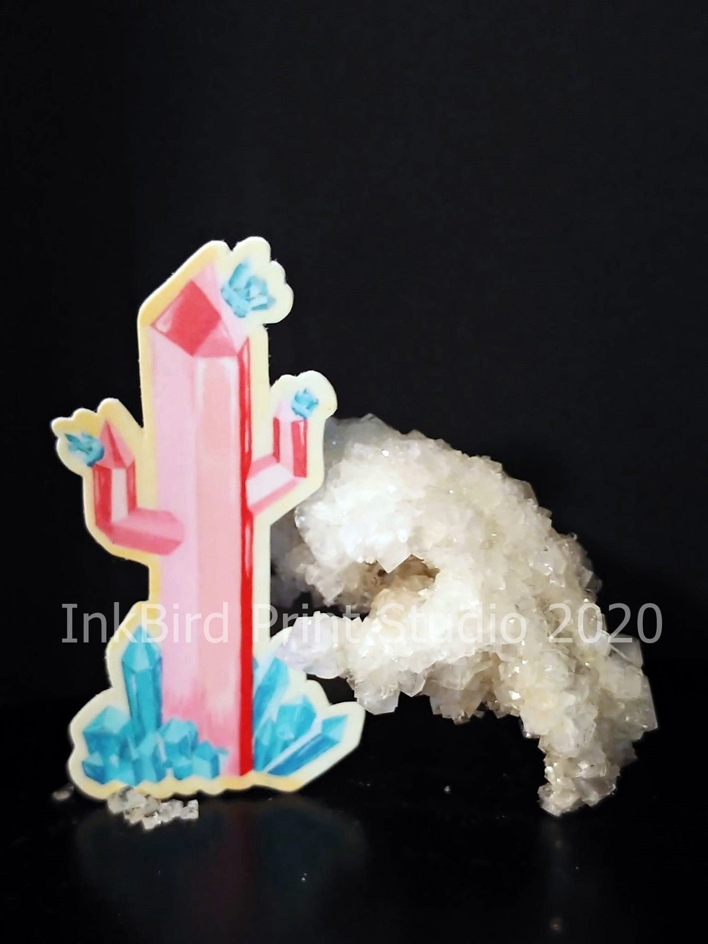 The Crystal Cactus Decal/Sticker, featuring a pink crystal with blue accents next to a cluster of translucent white crystals, stands out vividly against the black background. Perfect for laptops, gifts, water bottles, mirrors, lockers, and more. Text on the image states InkBird Print Studio LLC, 2020.