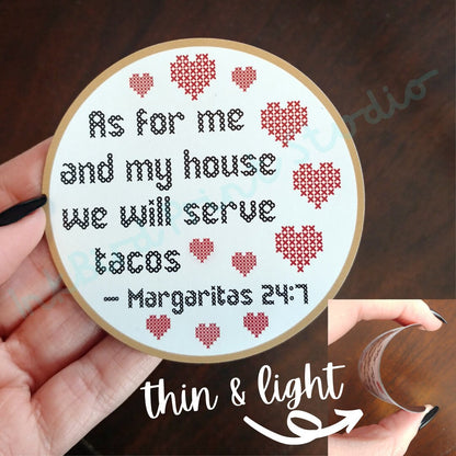Introducing the "As for me and my house, we will serve tacos. Margaritas 24:7" Cross Stitch Design Fridge Magnet by InkBird Print Studio LLC, featuring an elegant font encircled by red hearts. Perfect as a housewarming gift, it shows its delicate thickness with "thin & light," indicated by an arrow while held up effortlessly in hand.