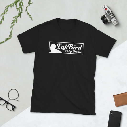 A sturdy black short-sleeve unisex t-shirt from InkBird Print Studio LLC, crafted from durable ring-spun cotton, showcasing the white InkBird Print Studio logo, is displayed on a surface alongside a camera, glasses, watch, and a plant.