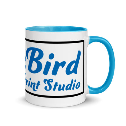 The InkBird Print Studio Logo Mug with Color Inside, from InkBird Print Studio LLC, is a white ceramic mug featuring a blue interior and handle. It displays the words "Bird Print Studio" in blue text surrounded by a black border. This vibrant design is dishwasher safe, combining style with practicality for everyday use.